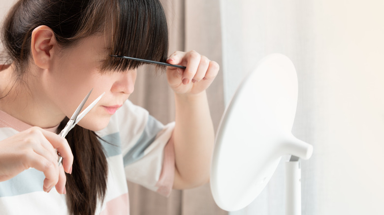 Woman cutting her own bangs