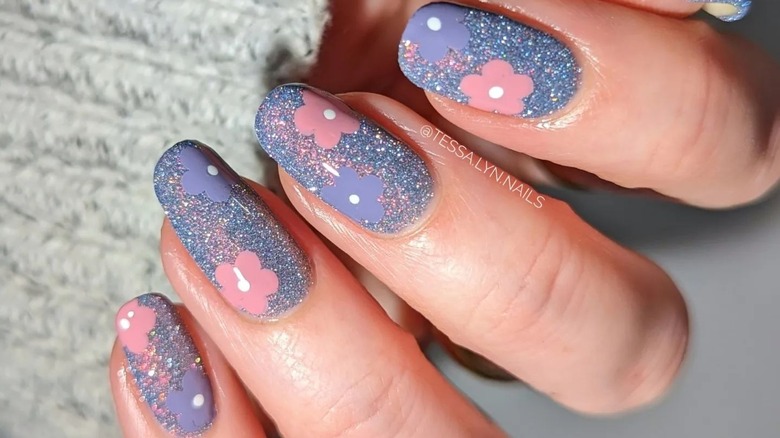 Sparkly nails accented with purple and pink flowers