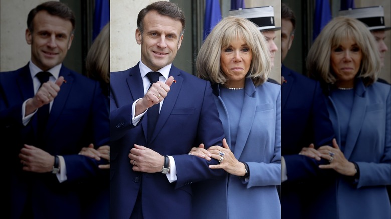 Emmanuel Macron giving a thumbs up while Brigitte holds his arm, both wearing blue