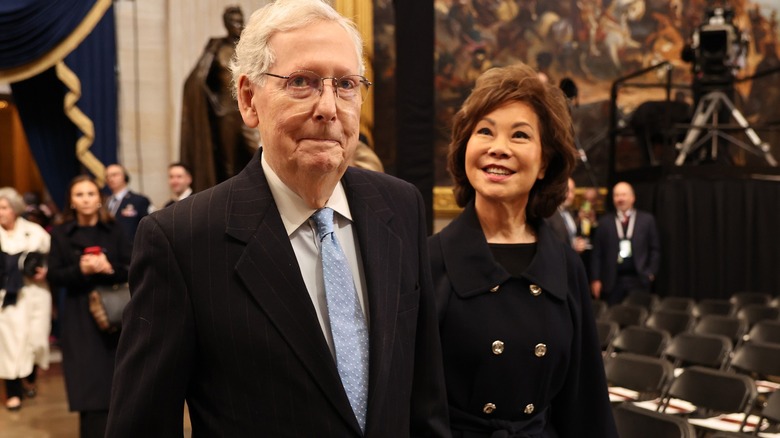 Elaine Chao smiling at Mitch McConnell as they walk through the Capitol