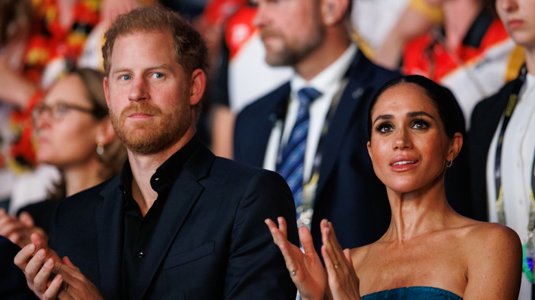 Prince Harry and Meghan Markle clapping in an audience