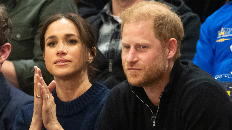 Closeup of Meghan Markle and Prince Harry sitting in bleachers