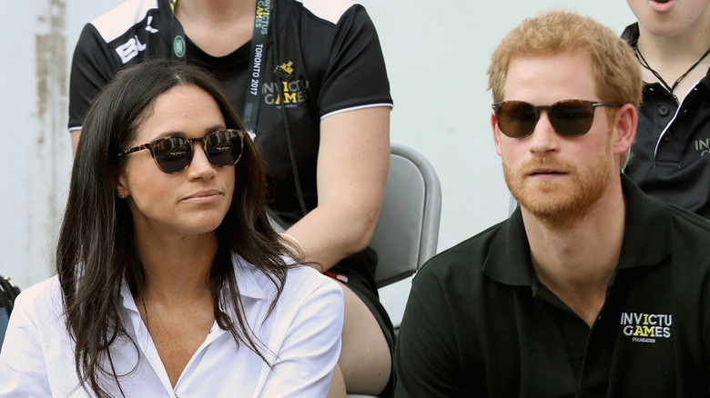 Meghan Markle and Prince Harry wearing sunglasses outside in audience of the Invictus Games