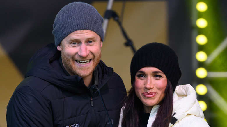 Prince Harry and Meghan Markle in beanie hats and puffer coats smiling