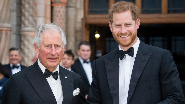 King Charles and Prince Harry smiling wearing tuxedos