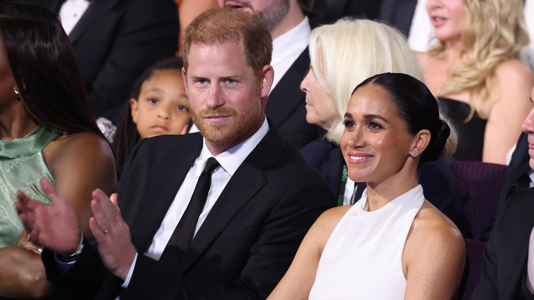 Prince Harry and Meghan Markle clapping in an audience