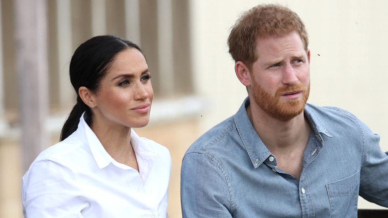 Meghan Markle and Prince Harry sitting next to each other looking serious