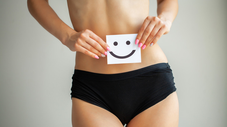 woman in her panties holding a smiling sign