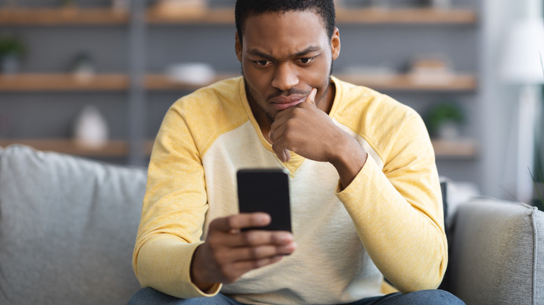 Man on couch stares at phone