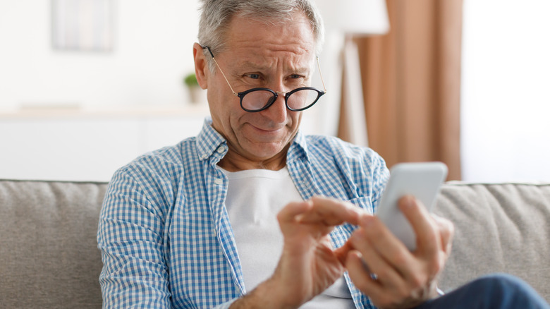 Man wearing glasses texting on couch