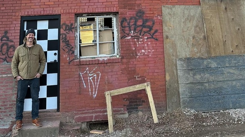 Steve Ford posing in front of dilapidated building