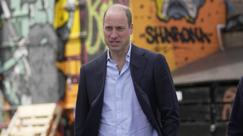 Prince William walking in front of graffiti wall