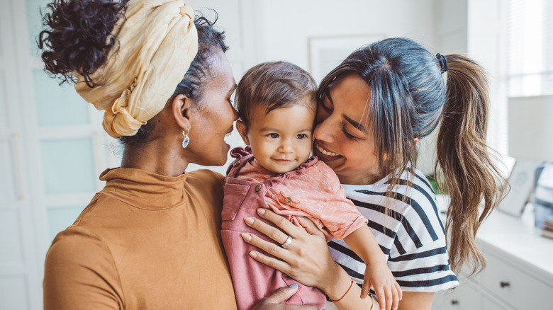 Two women embracing baby