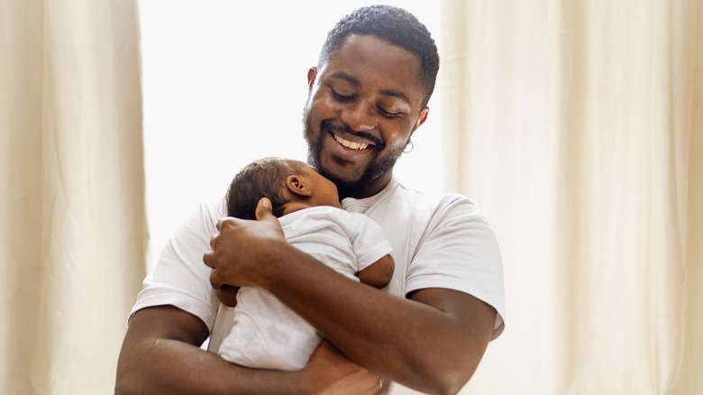 Man smiling while holding newborn baby