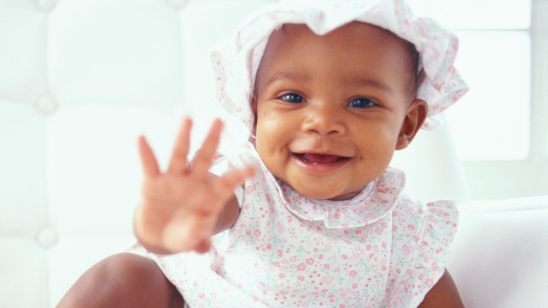 Baby in bonnet waving