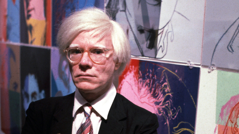 andy warhol standing in front of his art