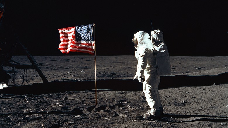 Buzz aldrin moon landing 1969, astronaut stands in front of american flag