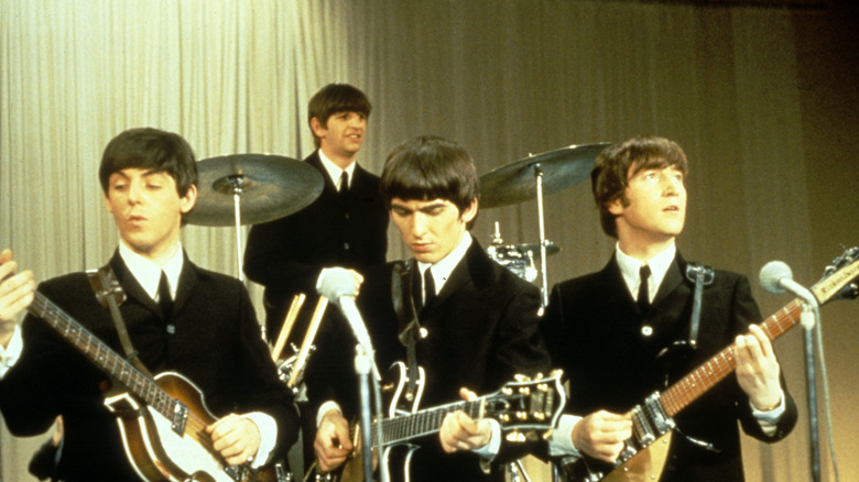 the beatles perform, all wearing suits