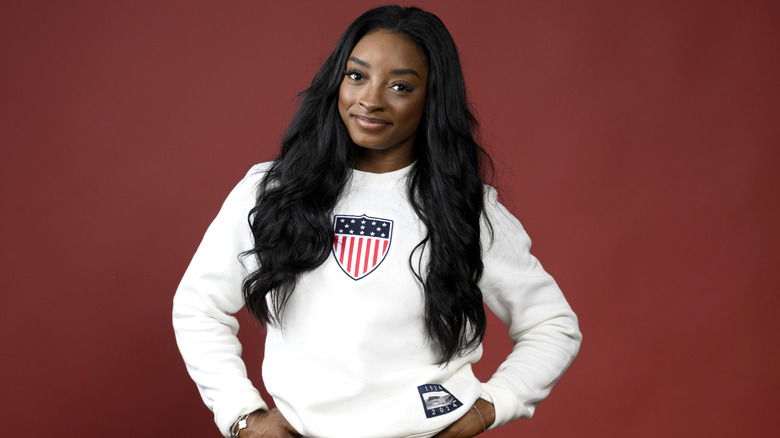 Simone Biles posing against red background