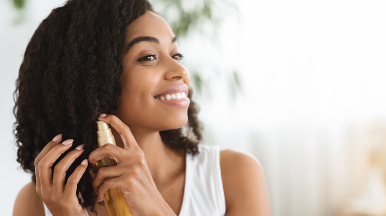 Woman spraying leave in conditioner to curly hair