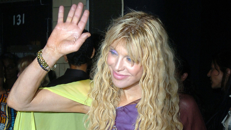 Courtney Love waving surrounded by fans taking pictures