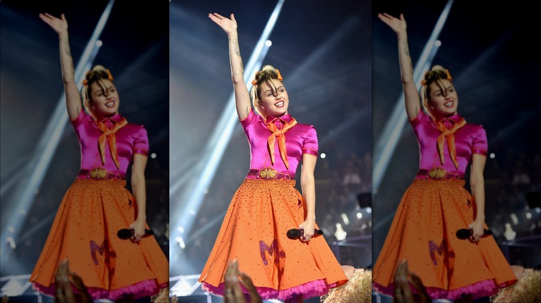 Miley Cyrus waving on stage in '50s costume