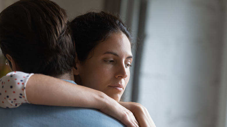 unhappy woman hugging husband