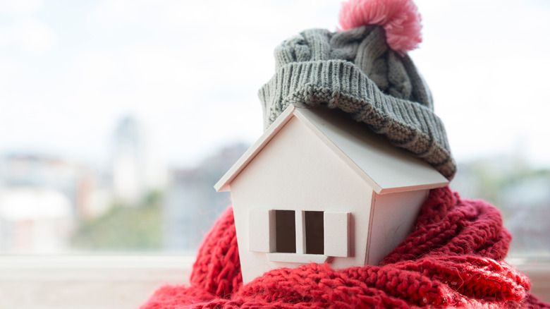 Miniature house wrapped in a beanie and scarf