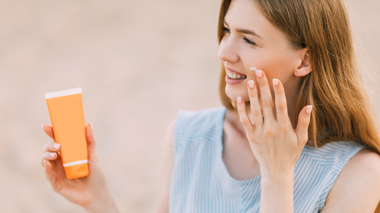 Woman applies sunscreen to face