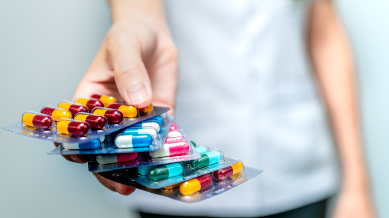 person holding several capsules in blister packs