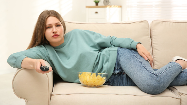 woman lying on the couch with a bowl of crisps