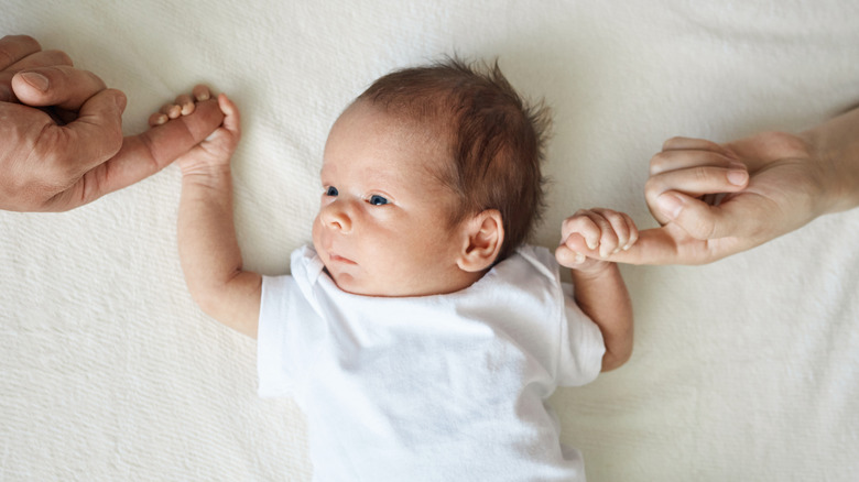 Baby holding parents' fingers with each hand