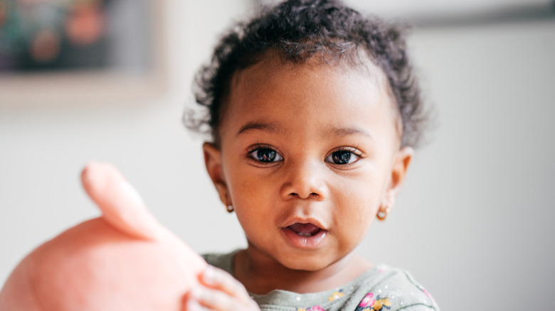 Black baby girl with golden earrings and a toy