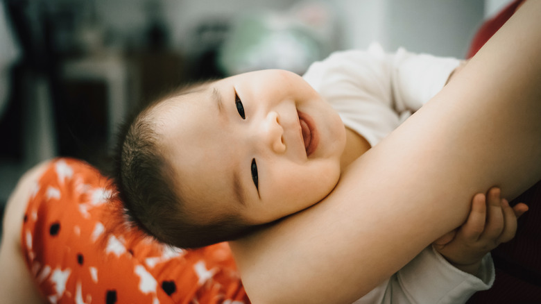 Asian baby smiling in mother's arms