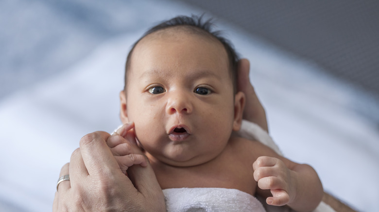 Baby looking up at adult holding his fingers