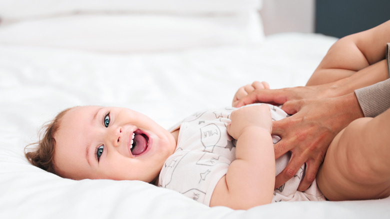 Adult's hands around laughing baby