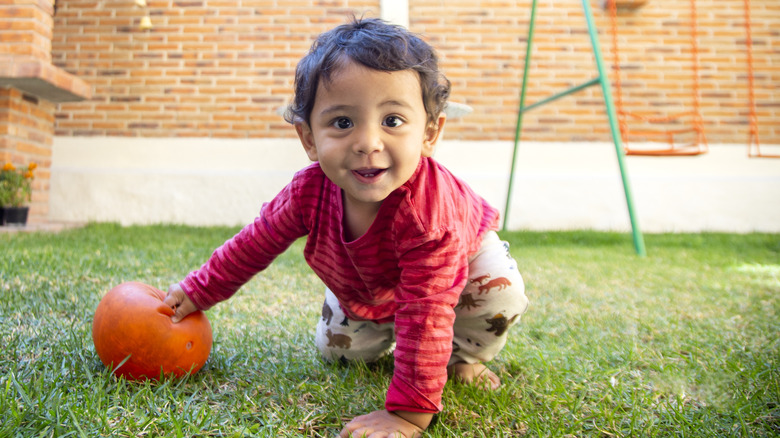 Little boy in red t-shirt crawling on grass