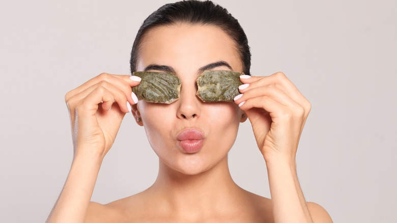 Woman applying teabags to eyes