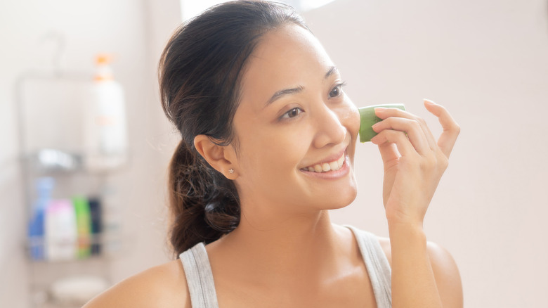 Woman rubbing aloe vera plant under eye