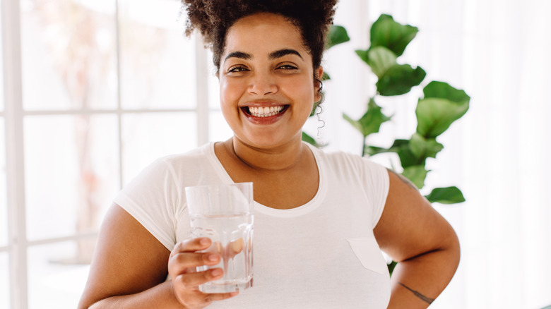 Woman smiling and holding a glass of water