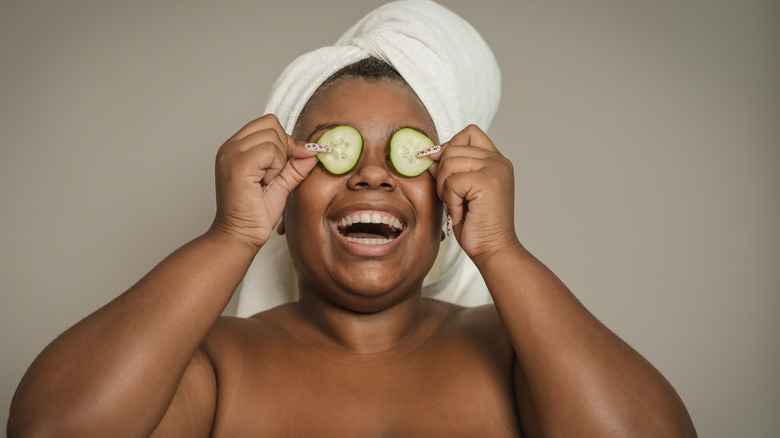 Woman laughing holding up cucumbers to eyes