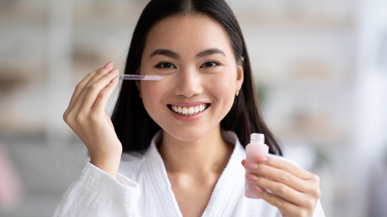 Woman smiling applying product under eye