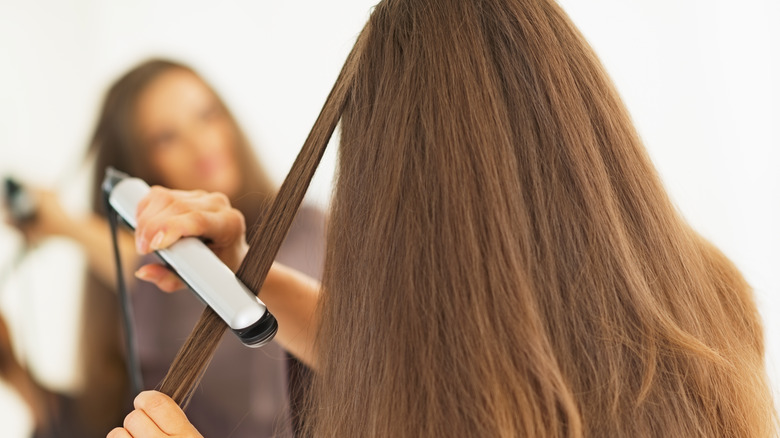 woman straightening hair with flat iron