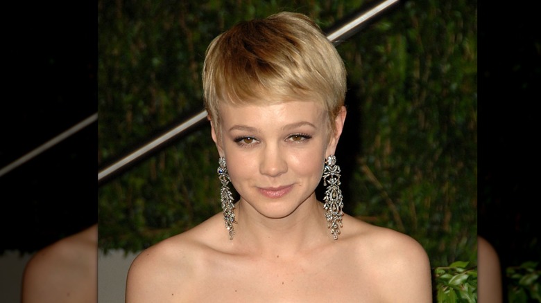 Carey Mulligan posing at the Vanity Fair Oscar party in 2010 with short blonde hair