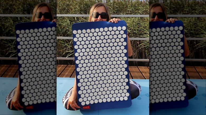 Woman holding an acupressure mat