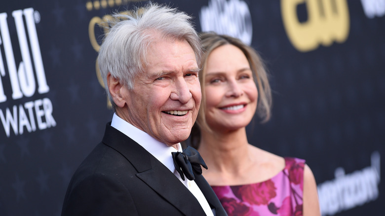 Harrison Ford looking at the camera with Calista Flockhart behind