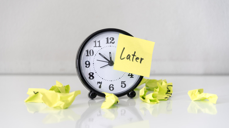 Alarm clock with a sticky note that reads "later"