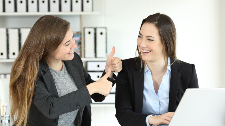 Woman giving thumbs up to other woman