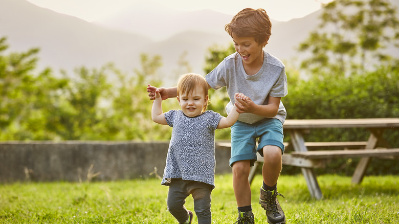 Older brother helping baby walk