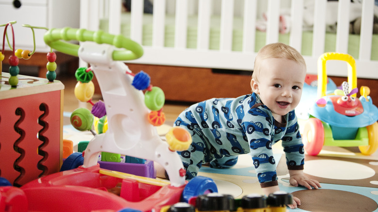 Baby boy crawling with toys